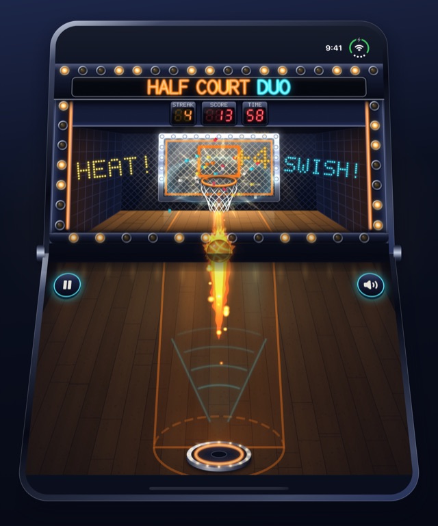 A phone folded like a laptop, the arcade cabinet on the raised half and the court on the half below. A ball on fire flies up from the pad, over the fold, toward the hoop, with HEAT and SWISH lit either side of the backboard.
